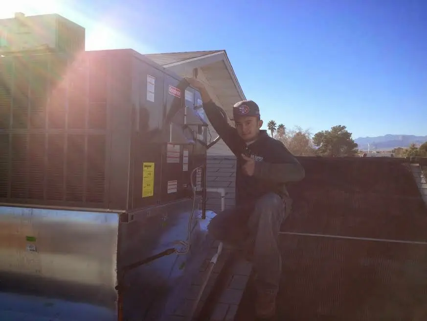 HVAC technician performing Air Duct Repair on a rooftop unit in University of California-Davis